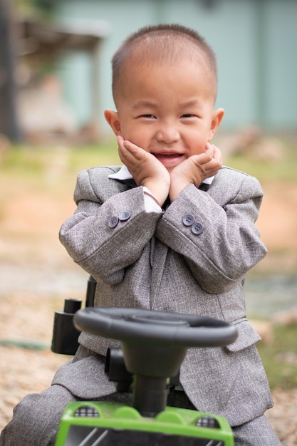 A smile children sitting on his toy car close up shot with blur background