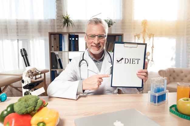 Smile doctor is holding diet sign in clinic room.