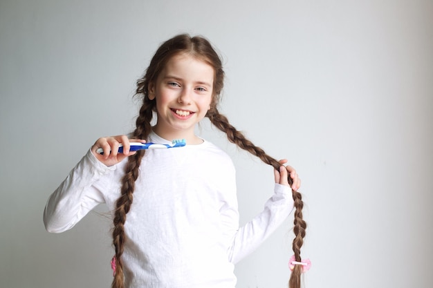 smile little girl brushing her teeth on a light background