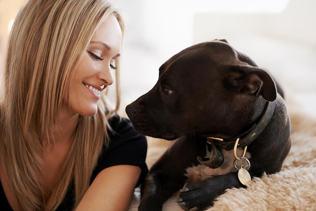 Smile love or woman and dog on a sofa with trust care and bonding at home together Pets face and female person relax with pitbull puppy in a living room with security protection or foster safety