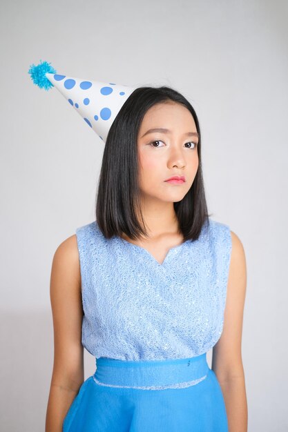 Smile young girl wear blue dress and a party hat on white background