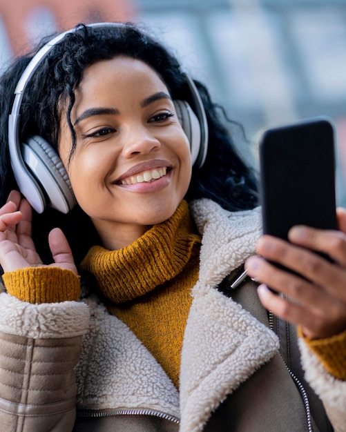 Smiley african american woman listening to music outdoors