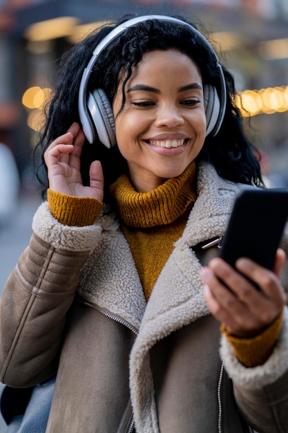 Smiley african american woman listening to music outside