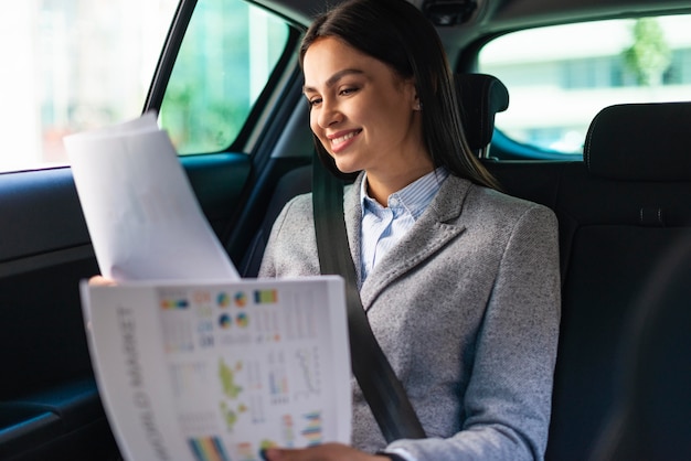 Smiley businesswoman in the car reviewing documents