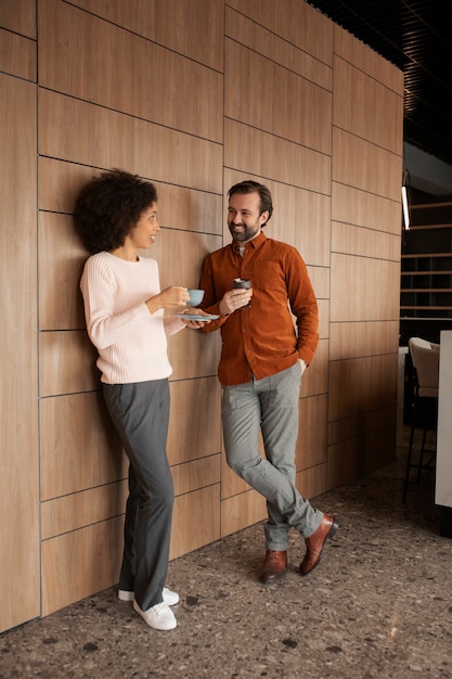 Smiley colleagues with coffee cups full shot