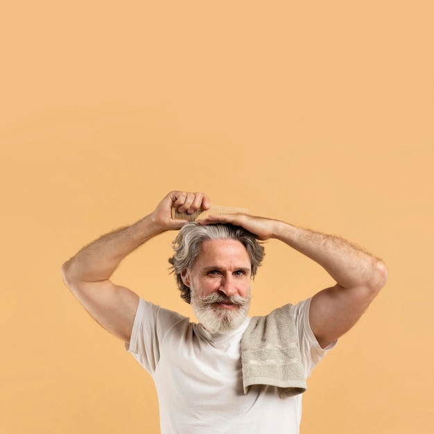 Smiley elder man combing his hair