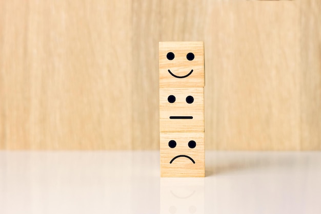 Smiley face happy and sad symbol on wooden block