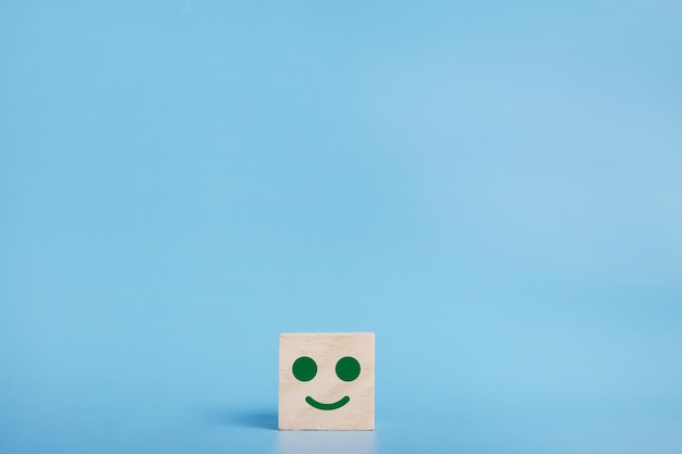 Smiley face icon on the wood cube, Customer service rating, Satisfaction survey concept.