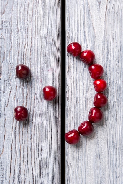 Smiley face made of cherries red fruit on wooden background stay healthy and be happy art is closer ...