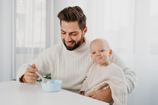 Smiley father at feeding time with his baby