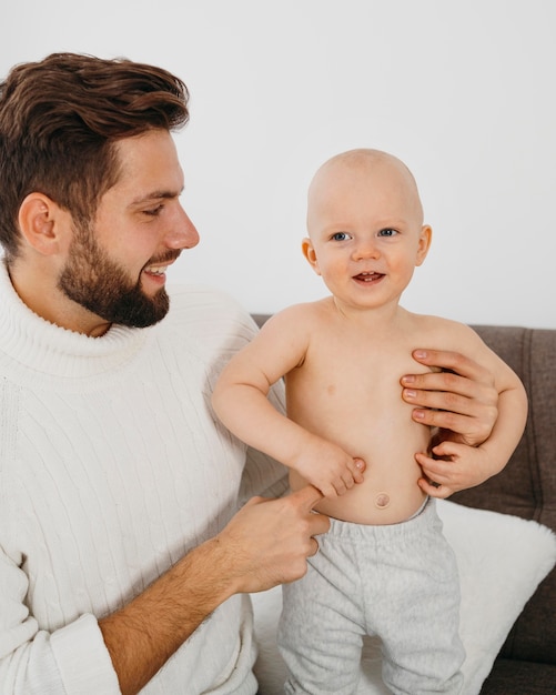 Smiley father spending time with his baby at home