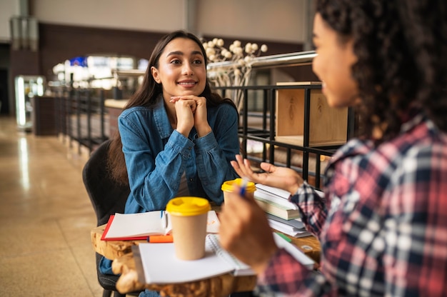 Smiley female friends having coffee and doing homework together