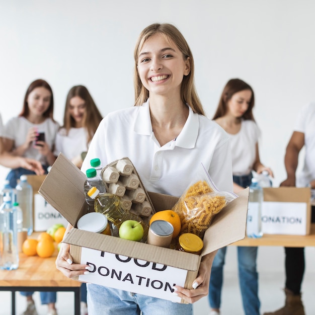 Smiley female volunteer holding box of food donations