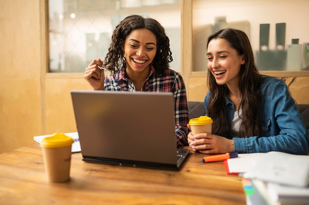 Smiley friends using laptop for homework while having coffee