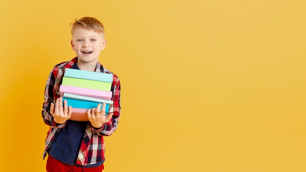 Smiley little boy with stack of books