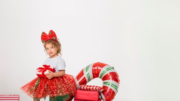 Smiley little girl surrounded by christmas elements with copy space