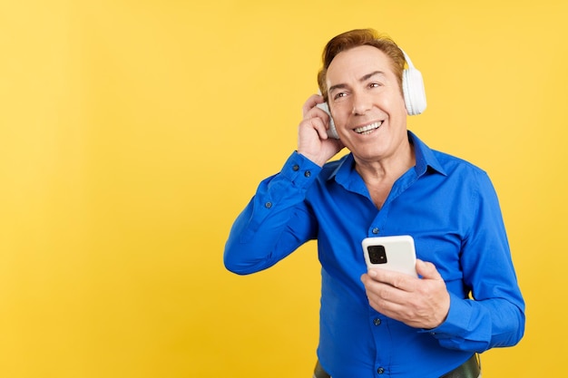 Smiley mature man listening to music with the mobile