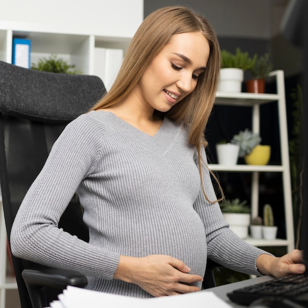 Smiley pregnant businesswoman at her desk in the office