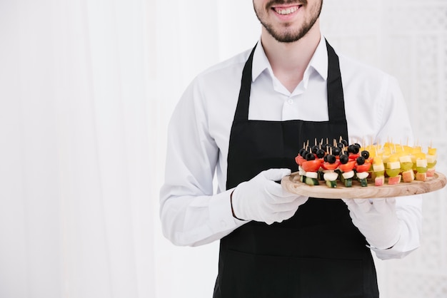 Smiley waiter holding snacks on a plate