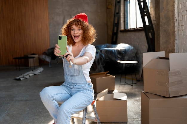 Smiley woman taking selfie with smartphone in her new home