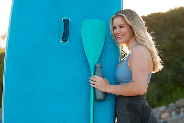 Smiley woman with paddleboard medium shot