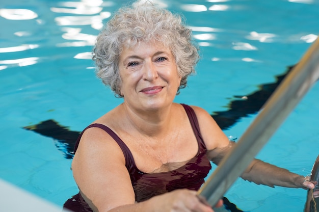 Smiling active senior woman entering in a swimming pool