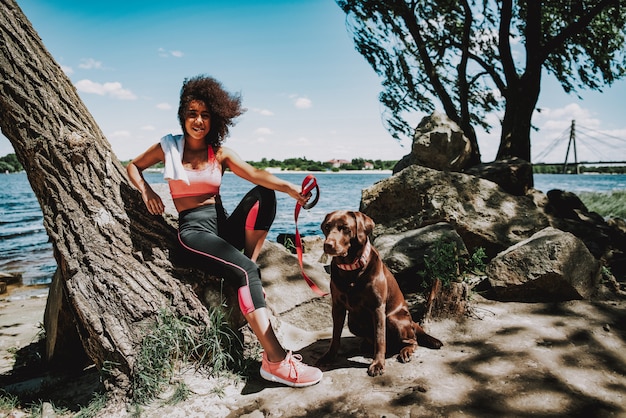 Smiling African American Girl with Dog Outdoors.