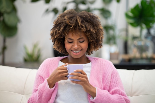 Smiling african american woman looking into coffee mug