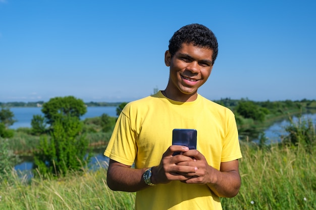 Smiling african american young man communicates on social networks outdoors