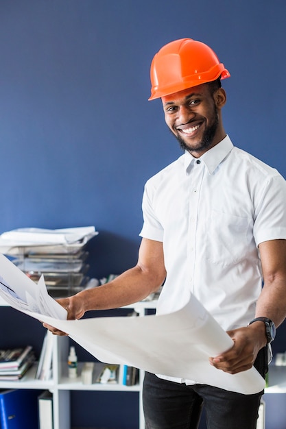 Smiling african architect holding blueprint