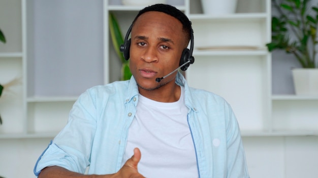 Smiling african professional call center operator wear wireless headset afro american businessman customer technical customer support service