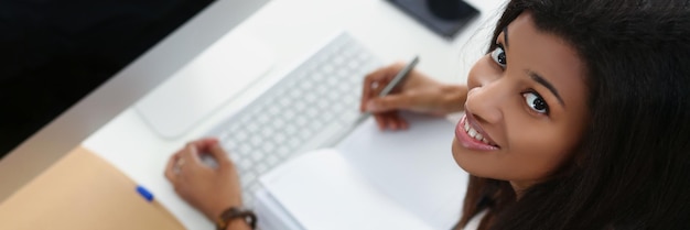 Smiling afro american young woman on workplace open journal luxury device on workplace