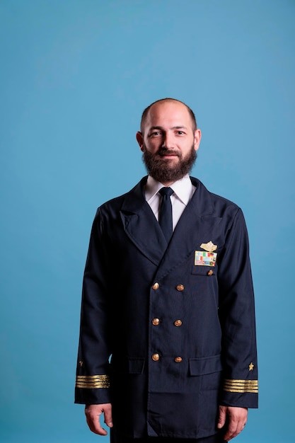 Smiling airplane captain wearing uniform medium close up portrait, plane aviator looking at camera. Middle age pilot with civil badge on professional suit, aircrew member