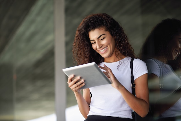 Smiling Arab girl using digital tablet in business background. 