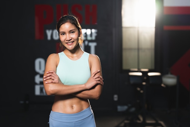 Smiling Asian athlete woman in sportswear standing arm crossed posing after exercise in fitness gym