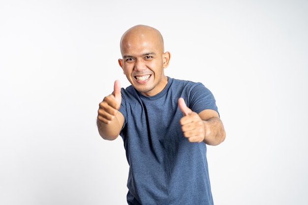 Smiling asian bald man showing two thumbs up while standing