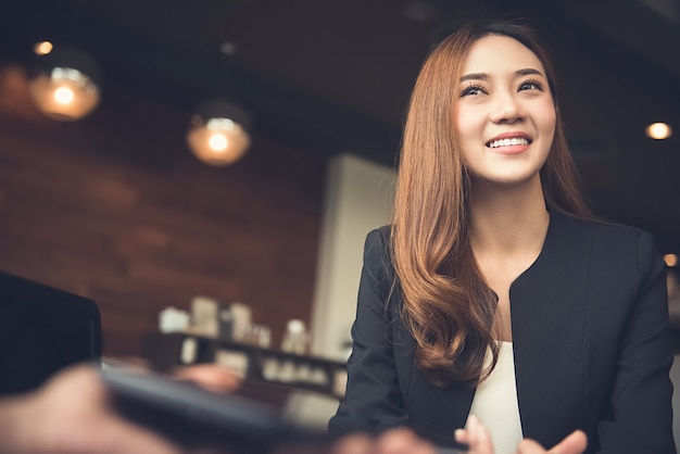 Smiling Asian business woman meeting with client in cafe