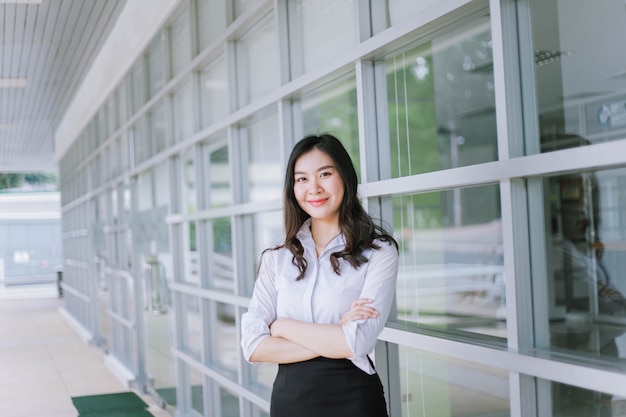 A smiling Asian business woman in white shirt crossed her arms