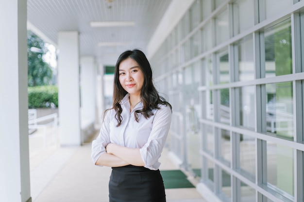 A smiling Asian business woman in white shirt crossed her arms