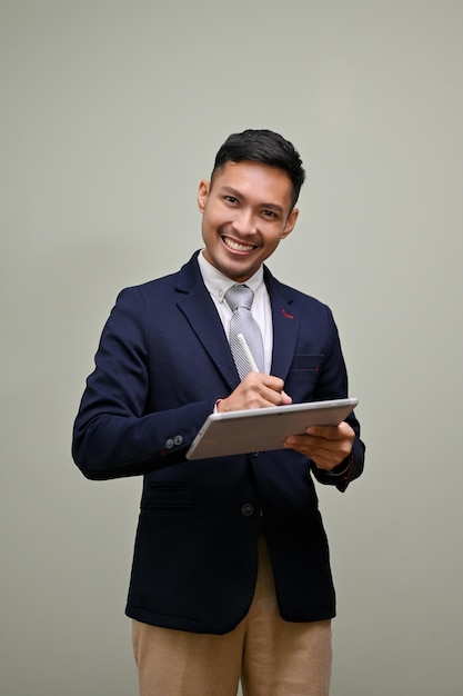 Smiling Asian businessmen using his digital tablet standing against an isolated background