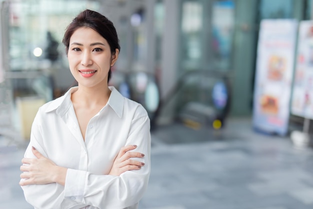 Smiling Asian businesswoman on blur office building background