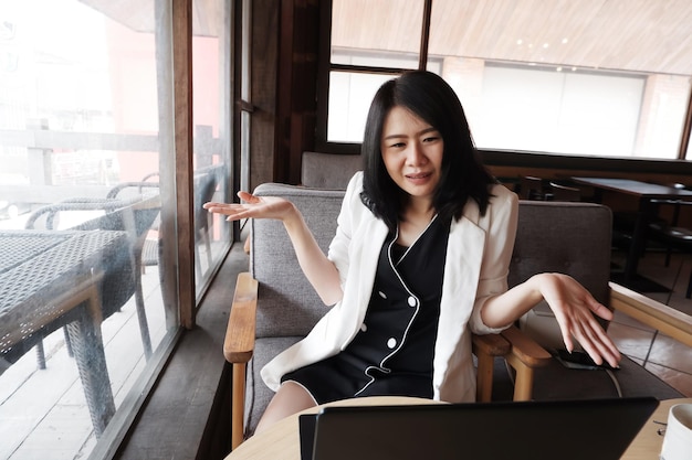 Smiling Asian businesswoman is online shopping in social media with laptop in coffee shop