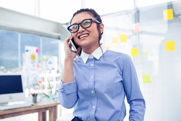 Smiling Asian businesswoman on phone call in office