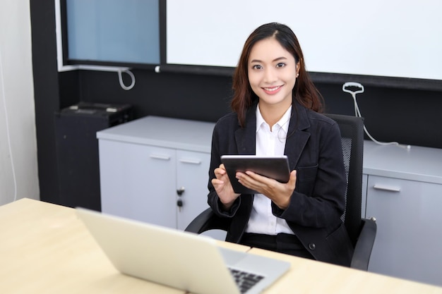 Smiling Asian businesswoman using tablet for work and Cute girl searching for some data and concentrate on her tablet in her office