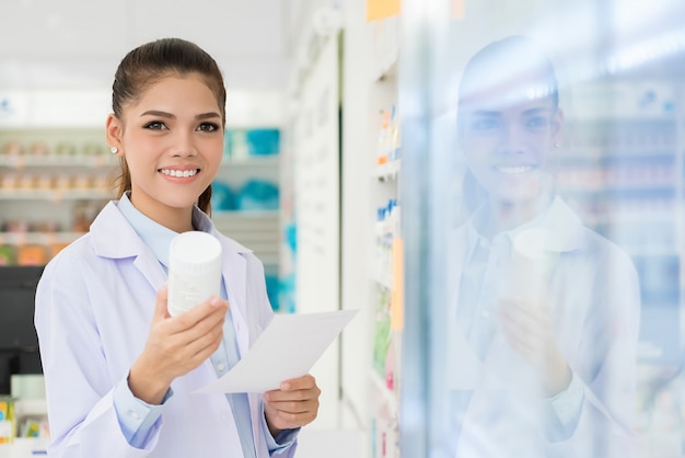 Smiling Asian female pharmacist working in chemist shop or pharmacy