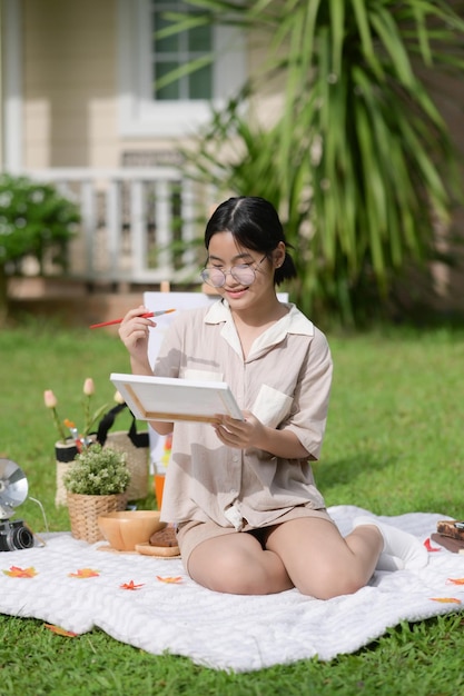 Smiling Asian girl having fun painting in garden at summertime