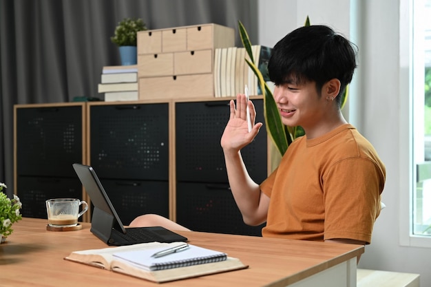 Smiling asian man having video call on computer tablet at home.