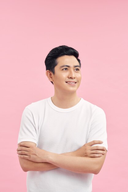 Smiling Asian man in t-shirt standing near blank wall.