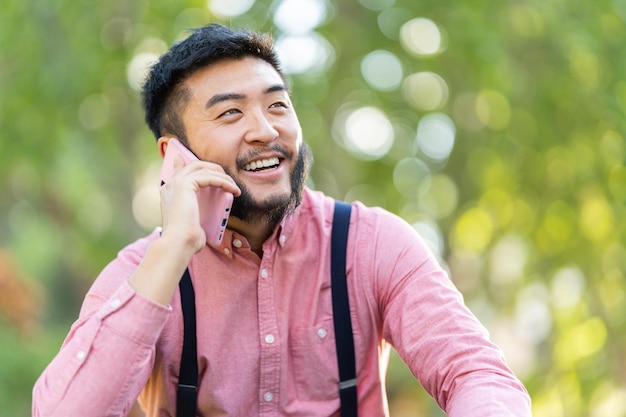 Smiling asian man talking to the mobile in a park