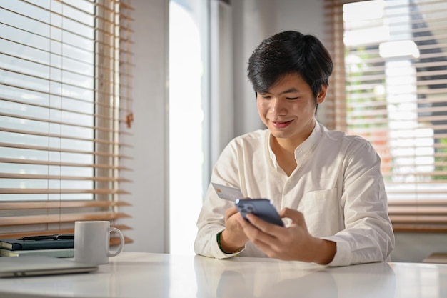 Smiling Asian man using mobile banking application to transfer money mobile banking